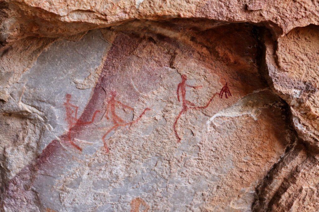Prehistoric cave carvings on rock walls showing early human life inside a cave.
